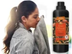 Woman sniffing a towel beside a tall black bottle labeled Tesori d’Oriente Japanese Rituals fragrance/oil.